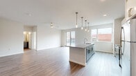 Located in the heart of Lancaster, PA, this well-appointed two-story residence offers four bedrooms, three bathrooms, and generous living space spread across two thoughtfully designed floors. The main level features an open-concept kitchen and living area with light wood-look flooring, recessed lighting, and a large central island topped with granite-style countertops. White cabinetry, stainless steel appliances, and elegant pendant lighting give the kitchen a clean, modern aesthetic. A bright staircase with a bold red handrail connects both levels seamlessly. The upper floor houses the bedrooms, each finished with plush carpeting and ceiling fans. The primary bedroom features a sliding glass door opening directly onto the private balcony, which overlooks a lush green roof and cityscape views. Spacious walk-in closets with wire shelving systems offer ample storage throughout. The bathrooms are finished with wood-look tile flooring and feature either a soaking tub or a walk-in shower with clean white surrounds and matte black hardware accents. Three closets and two staircases add to the home's functional layout, making this a highly livable and stylish urban residence.