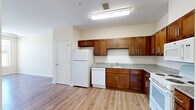 This 1-bedroom, 1-bathroom residence in San Francisco offers a thoughtfully designed single-floor layout that maximizes functionality and comfort. The kitchen is a standout feature, equipped with rich warm-toned wood cabinetry, granite-style countertops, and white appliances including a refrigerator, dishwasher, and range with overhead microwave. Light wood laminate flooring runs throughout the main living areas, creating a clean, cohesive aesthetic that enhances the sense of openness. A wide entryway connects the kitchen to the living area, providing an easy flow between spaces. The bedroom is carpeted for added comfort and features a ceiling fan, a well-sized window that invites natural light and outdoor views, and two closets — including a double-door closet offering generous storage. The bathroom is finished with large-format tile flooring, a combination tub and shower with white subway tile surround, a wood-toned vanity with a sink, a medicine cabinet, and a walk-in shelving closet area. Neutral wall tones throughout the unit contribute to a bright, calm ambiance. This residence combines practical amenities with a clean, move-in-ready design well-suited to urban living in San Francisco.
