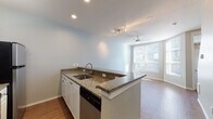 This three-story residence on S Harbor Pl in Portland, Oregon, is thoughtfully laid out across multiple levels connected by an interior staircase. The entry level features a tiled foyer with recessed lighting, a built-in mail shelf, and access to an attached private garage with an automatic opener—a practical convenience in the Pacific Northwest.

The main living level showcases warm wood-style flooring throughout an open-concept layout. The kitchen is equipped with granite countertops, white cabinetry, stainless steel appliances including a range and dishwasher, and a peninsula with a sink that opens directly to the living area. A ceiling fan and large windows allow natural light to fill the space, creating a bright and airy atmosphere.

Upper levels feature carpeted bedrooms with ceiling fans and generous window arrangements that invite natural light. The bathroom includes a wide vanity with a dark countertop and ample mirror space. A dedicated laundry area houses a full-sized washer and dryer with overhead wire shelving for additional storage. The neutral color palette and clean finishes give the home a consistent, move-in-ready aesthetic throughout all three floors.