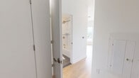 Located at 6320 Shakespeare St in Pittsburgh's East End neighborhood, this studio unit offers a thoughtfully designed open-concept layout on a single floor. Light hardwood flooring runs throughout the main living area, complementing the bright, neutral palette of white walls and clean contemporary finishes.

The living area is anchored by two large windows that frame elevated views of the Pittsburgh skyline, surrounding rooftops, and the rolling hillside beyond — filling the space with abundant natural light. A built-in shelving unit and cabinetry add functional storage with a warm wood-toned aesthetic.

The kitchen is well-appointed with white upper cabinetry extending to the ceiling, natural wood-toned lower cabinets with gold hardware, a classic white subway tile backsplash, and a full suite of stainless steel appliances including a range, microwave, dishwasher, and refrigerator. A window above the countertop continues the theme of natural light throughout.

The bathroom is finished with large-format tile flooring, a soaking tub with full subway tile surround, a wood-vanity with white countertop, and a backlit mirror — delivering a clean, modern spa-like atmosphere.

The entrance provides a practical transition into the unit, completing this efficiently designed and stylishly finished Pittsburgh residence.