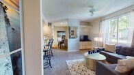 This single-floor residence offers a thoughtfully designed open-concept layout that connects the living, dining, and kitchen areas into one cohesive space. The living room is bright and inviting, featuring large windows that allow abundant natural light to fill the room, carpeted flooring, a ceiling fan, and ample space for comfortable seating arrangements. A half-wall partition subtly defines the dining area, which includes room for a full dining table and sits adjacent to both the kitchen and living space.

The kitchen is efficiently laid out with light wood cabinetry extending to the ceiling for generous storage, laminate countertops, and full white appliances including a refrigerator, electric range, and over-the-range microwave. A breakfast bar with seating bridges the kitchen to the main living area.

The residence includes two carpeted bedrooms, each featuring windows with outdoor views, neutral tones, and walk-in or reach-in closet space. The accent wall in each bedroom adds a touch of character to the otherwise neutral palette.

A full bathroom serves the residence, finished with tile flooring, a vanity, and a shower-tub combination. A dedicated in-unit laundry room houses a full-size washer and dryer with an overhead storage shelf, adding everyday convenience to this well-rounded home.