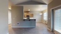 Located at 5839 Reed Ln SE in Salem, Oregon, this single-floor residence offers a thoughtfully designed layout with contemporary finishes throughout. The open-concept living and dining area is anchored by a peninsula-style kitchen that features flat-front cabinetry in a warm wood-tone finish, white countertops, and a full suite of stainless steel appliances including an electric range, over-the-range microwave, and refrigerator. A pendant light fixture hangs above the peninsula, adding a polished accent to the space. Wood-look plank flooring extends throughout the main living areas, contributing to a clean, modern aesthetic.

The living area benefits from multiple windows that allow natural light to fill the space, complemented by vaulted ceiling details that enhance the sense of openness. A glass-panel door provides direct access to an outdoor area, further connecting the interior to the outside.

The bedrooms offer a quieter retreat; one features vaulted ceilings and wood-look flooring, while another is finished with plush carpeting and a window with exterior views. Two bathrooms serve the unit, each with wood-tone vanity cabinetry and white countertops. One bathroom includes a walk-in shower, while the other offers additional storage cabinetry and grab bar accessibility features.