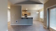Located at 5839 Reed Ln SE in Salem, Oregon, this single-floor residence offers a thoughtfully designed layout with contemporary finishes throughout. The open-concept living and dining area is anchored by a peninsula-style kitchen that features flat-front cabinetry in a warm wood-tone finish, white countertops, and a full suite of stainless steel appliances including an electric range, over-the-range microwave, and refrigerator. A pendant light fixture hangs above the peninsula, adding a polished accent to the space. Wood-look plank flooring extends throughout the main living areas, contributing to a clean, modern aesthetic.

The living area benefits from multiple windows that allow natural light to fill the space, complemented by vaulted ceiling details that enhance the sense of openness. A glass-panel door provides direct access to an outdoor area, further connecting the interior to the outside.

The bedrooms offer a quieter retreat; one features vaulted ceilings and wood-look flooring, while another is finished with plush carpeting and a window with exterior views. Two bathrooms serve the unit, each with wood-tone vanity cabinetry and white countertops. One bathroom includes a walk-in shower, while the other offers additional storage cabinetry and grab bar accessibility features.