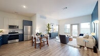Located in Houston, TX, this 2-bedroom, 1-bathroom residence offers a thoughtfully designed open-concept layout that seamlessly connects the kitchen, dining, and living areas. The kitchen is finished with two-tone cabinetry — crisp white uppers paired with bold navy lowers — stainless steel appliances including a refrigerator, range, microwave, and dishwasher, and light wood-look flooring that extends throughout the main living spaces. The bright living room features a striking teal accent wall, large windows, and a glass door that fills the space with natural light and provides outdoor views. The generously sized primary bedroom showcases a teal accent wall with plush carpeting, a ceiling fan, and a large window. It connects to a spacious walk-in closet outfitted with multi-tiered shelving and hanging rods. The second bedroom is well-proportioned with easy access to additional closet space. The full bathroom offers a tub/shower combination with white subway tile surround, a granite-topped vanity, and wood-look flooring. A dedicated in-unit laundry closet houses a full-size washer and dryer. Throughout the home, high ceilings and a neutral color palette create a bright, airy atmosphere.