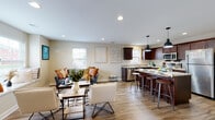Located at 20151 Gilbert Rd in Big Rapids, Michigan, this two-story residence offers a well-designed layout spread across two levels. The main floor centers around an open-concept living and kitchen area, where hardwood-style flooring flows throughout. The kitchen is a standout feature, equipped with rich dark-wood cabinetry, stainless steel appliances including a range, microwave, dishwasher, and refrigerator, and a granite-topped island with bar seating. Pendant lighting accents the island, while recessed lighting illuminates the space throughout. The living area connects seamlessly to the kitchen, offering a built-in window seat that provides views of the surrounding area and fills the space with natural light.

Bedrooms are found on both floors, each featuring neutral-toned carpet, large windows that invite natural light, and ample wall space. The bathrooms are finished with dark wood vanities, white countertops, stone-look tile flooring, and chrome hardware accents. Additional carpeted rooms provide flexible space suitable for various uses. The overall design maintains a consistent, neutral color palette with warm beige tones, creating a cohesive and inviting ambiance throughout the home.