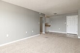 Located at 207 Galley Rd in Colorado Springs, CO 80909, this single-floor unit offers a straightforward and functional layout across several well-defined living spaces. The living area is generously sized, featuring neutral-toned carpet flooring, soft gray walls, a textured ceiling, and a baseboard heating system. A window allows natural light to filter in, creating a bright and open atmosphere. The space flows naturally into a kitchen area defined by tile flooring, white cabinetry with ample storage both above and below the counter, tile countertops with a wood trim accent, a stainless steel double sink, and white appliances including a refrigerator and an electric range. A pass-through counter connects the kitchen to the main living area, enhancing the open feel. The unit includes multiple carpeted bedrooms, each finished with the same neutral gray palette, textured ceilings, white baseboards, and baseboard heaters, providing consistent and comfortable living spaces. The bathroom features tile flooring, a white vanity with under-sink storage, a wood-toned countertop, a lighted vanity mirror, and standard fixtures. Throughout the unit, the consistent use of neutral tones and functional finishes creates a clean, move-in-ready environment well suited for everyday living in Colorado Springs.