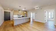 Located at 101 Laurel Hill Rd in Brookfield, CT, this thoughtfully designed 2-bedroom, 1-bathroom residence offers a clean, modern aesthetic across a single floor. Light-toned hardwood flooring runs seamlessly throughout, unifying the open-concept living space and creating a warm, cohesive ambiance.

The combined living, dining, and kitchen area serves as the heart of the home. The kitchen is appointed with natural wood flat-front cabinetry, white subway tile backsplash, stainless steel appliances including a refrigerator and range, and a large waterfall-edge island with a black fixture sink — ideal for both meal prep and casual dining. Pendant globe lights add a stylish touch overhead.

Both bedrooms feature neutral walls, hardwood flooring, and black-framed windows that invite natural light. The primary bedroom includes a sliding barn-style door opening to outdoor views. A second bedroom features a double window with exterior views of the surrounding neighborhood.

The bathroom is well-appointed with a floating wood vanity, white countertop, a glass-enclosed walk-in shower with neutral tile surround, and accessibility-friendly grab bars. An in-unit laundry area houses a full-size front-loading washer and dryer. Three closets and a hallway complete the efficiently organized layout.