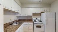 Located at 1414-1422 SOM Center Rd in Mayfield Heights, Ohio, this single-floor residence offers a practical and comfortable layout designed for everyday living. The kitchen is well-appointed with white cabinetry providing ample storage, granite-style countertops, a double basin sink, and white appliances including a gas range and full-size refrigerator. Light-colored tile flooring in the kitchen transitions seamlessly to plush carpeting throughout the living and bedroom areas. The open living space is generously sized, featuring a ceiling fan and a neutral color palette that lends itself to a variety of furnishing styles. A partial wall creates a natural division between the living area and the kitchen entry, adding architectural interest to the floor plan. The bedrooms are well-proportioned, each offering wall-to-wall carpeting, natural light through standard windows with vertical blinds, and closet storage. One bedroom includes a built-in closet with a hanging rod, offering practical organization. The bathroom features tile flooring, tile wainscoting, and granite-style countertops consistent with the kitchen's finishes. Throughout the residence, clean white trim, neutral wall tones, and consistent finishes create a cohesive and move-in-ready environment.