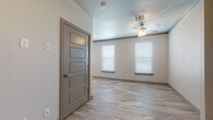 Located at 170 Vin Marbella Dr in El Paso, Texas, this single-story home delivers a clean, modern aesthetic with thoughtfully selected finishes throughout. Large-format marble-look tile flooring runs continuously across the living areas, creating a cohesive and polished look that ties the entire floor plan together.

The kitchen is a standout feature, designed in a galley layout with ample cabinetry in a contemporary taupe finish. Granite countertops provide generous prep space, while a decorative tile backsplash in a mixed geometric pattern adds visual texture. Stainless steel appliances — including a refrigerator, electric range, built-in microwave, and dishwasher — complete this well-equipped space.

The living and bedroom areas are bright and open, each benefiting from multiple windows dressed with horizontal blinds that allow for controlled natural light. Ceiling fans with integrated lighting fixtures are installed in these rooms, adding both comfort and functionality. Five-panel interior doors in a coordinating gray tone lend a refined architectural detail throughout.

The bathroom is elegantly appointed with a glass-enclosed walk-in shower featuring bold, veined tile surrounds in a chevron accent pattern. A granite-topped vanity with an undermount sink and a large framed mirror rounds out the space, maintaining the home's consistent upscale character.