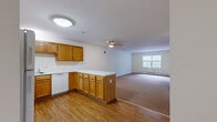 Located at 36 Greenleaves Dr in Hadley, Massachusetts, this single-floor residence offers three bedrooms and two bathrooms within a thoughtfully arranged floor plan. The open-concept kitchen and living area serves as the heart of the home, where warm honey-toned wood cabinetry, white appliances — including a refrigerator, electric range, and dishwasher — and a peninsula with a light-colored countertop create a functional and welcoming cooking space. The kitchen transitions seamlessly into the living room, which features a ceiling fan, a baseboard heating unit, and carpet flooring that extends throughout the living and sleeping areas, while the kitchen enjoys durable wood-look flooring. The living room is bright and open, with natural light filtering in through a window overlooking the outdoors. Each of the three bedrooms is carpeted and finished with neutral tones, offering a calm and comfortable atmosphere. The primary bedroom is generously sized, with a closet featuring a sliding door and rail system. Additional bedrooms receive natural light through windows with blinds. The bathrooms include wood-look flooring, and the overall interior maintains a clean, neutral palette throughout. Baseboard heating is present in multiple rooms, ensuring consistent comfort year-round.