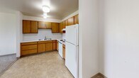 Located at 1220 Estes Park Ct in Rapid City, South Dakota, this 2-bedroom, 1-bathroom single-floor unit offers a straightforward and functional layout across a comfortable footprint. The space is organized to maximize practicality, with each room clearly defined and easily accessible.

The kitchen features warm oak-toned cabinetry extending along two walls, offering ample upper and lower storage. White appliances, including a refrigerator, electric range, and dishwasher, complement the light tile flooring, creating a clean and efficient cooking space.

Both bedrooms are carpeted and bathed in natural light through large windows that frame outdoor greenery and surrounding landscape views. Baseboard heating is present in each room. The primary bedroom includes a window-unit air conditioner and connects to a spacious walk-in closet with built-in shelving and hanging rods. A second closet provides additional storage elsewhere in the unit.

The bathroom features tile flooring, an oak vanity with storage below, and a clean, neutral color palette consistent throughout the unit.

The living room offers a generously proportioned open area with soft carpet and bright, neutral walls, providing a versatile space for various furniture arrangements. Overall, the unit maintains a clean, understated aesthetic throughout.