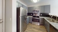Located at 13 Harbison Way in Columbia, SC, this single-floor residence offers a well-designed layout that balances comfort and modern style. The kitchen is a standout feature, showcasing gray shaker-style cabinetry, granite countertops, a dark subway tile backsplash, wood-look vinyl flooring, and a full suite of stainless steel appliances, including a refrigerator, electric range, and over-the-range microwave. The living and bedroom areas are finished with plush neutral carpeting and textured ceilings, creating a cozy and inviting atmosphere. Ceiling fans are present in the bedrooms, promoting air circulation and comfort. The primary bedroom includes a built-in desk nook, a walk-in closet, and direct access to an en suite bathroom. The bathrooms are tastefully appointed with gray vanity cabinetry, light countertops, wood-look vinyl flooring, and brushed nickel fixtures. The primary bath features a soaking tub and shower combination, while a second bathroom offers a streamlined single-vanity layout. Throughout the residence, a consistent neutral color palette and clean finishes create a cohesive, move-in-ready aesthetic. Additional practical features include a utility panel access point and ample storage throughout the home.