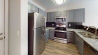 Located at 13 Harbison Way in Columbia, SC, this single-floor residence offers a well-designed layout that balances comfort and modern style. The kitchen is a standout feature, showcasing gray shaker-style cabinetry, granite countertops, a dark subway tile backsplash, wood-look vinyl flooring, and a full suite of stainless steel appliances, including a refrigerator, electric range, and over-the-range microwave. The living and bedroom areas are finished with plush neutral carpeting and textured ceilings, creating a cozy and inviting atmosphere. Ceiling fans are present in the bedrooms, promoting air circulation and comfort. The primary bedroom includes a built-in desk nook, a walk-in closet, and direct access to an en suite bathroom. The bathrooms are tastefully appointed with gray vanity cabinetry, light countertops, wood-look vinyl flooring, and brushed nickel fixtures. The primary bath features a soaking tub and shower combination, while a second bathroom offers a streamlined single-vanity layout. Throughout the residence, a consistent neutral color palette and clean finishes create a cohesive, move-in-ready aesthetic. Additional practical features include a utility panel access point and ample storage throughout the home.