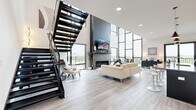 This contemporary residence in Oakdale, Minnesota, offers 2240 square feet of meticulously designed living space across two floors. The home boasts three bedrooms and three bathrooms, with the primary bedroom spanning a generous 170 square feet. The ground floor encompasses 1140 square feet, while the upper level provides 1100 square feet of space.

The heart of the home is an expansive open-concept area combining the kitchen and living room. The gourmet kitchen features sleek, dark cabinetry, state-of-the-art stainless steel appliances, and a large island with seating. Pendant lighting adds a touch of modern elegance. The living area is highlighted by floor-to-ceiling windows that flood the space with natural light and offer panoramic views of the surrounding landscape.

A striking linear fireplace serves as a focal point in the living room, complemented by a wall-mounted TV and contemporary furnishings. The home's design emphasizes clean lines and a neutral color palette, creating a sophisticated and serene ambiance. Light wood flooring throughout enhances the sense of spaciousness and continuity.

The bedrooms are thoughtfully appointed, with the primary suite featuring large windows and minimalist decor. Bathrooms showcase modern fixtures and finishes, including floating vanities and frameless glass shower enclosures. Additional amenities include a dedicated laundry room with high-efficiency appliances and ample storage solutions throughout.

A glass-railed staircase and upper-level hallway maintain the home's open feel while providing access to the second floor. The property's attention to detail extends to every corner, from the carefully curated artwork to the strategically placed lighting, resulting in a harmonious and luxurious living environment.