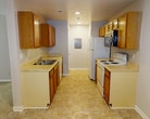 Located at 55 Colony Square Ct, Unit 11, in Newport News, VA 23602, this single-floor apartment offers 1,040 square feet of practical living space across three bedrooms and two bathrooms. The galley-style kitchen is equipped with warm oak cabinetry, light countertops, a double stainless steel sink, a coil-burner electric range, a built-in microwave, a dishwasher, and a refrigerator, all set over durable tile flooring. Each of the three bedrooms features neutral carpet flooring and a ceiling fan with an integrated light fixture. The primary bedroom spans 190 square feet and includes access to a closet, providing ample storage. The additional bedrooms are similarly appointed with windows offering natural light and views of surrounding greenery. Both bathrooms feature oak vanity cabinets with white countertops, large wall mirrors, and overhead lighting. One bathroom includes a closet visible in its mirror reflection, indicating proximity to additional storage. The unit maintains a consistent neutral color palette throughout, with white trim and light-toned walls creating a clean, cohesive aesthetic. Ceiling fans in every bedroom contribute to year-round comfort and ventilation across this efficiently designed single-level home.