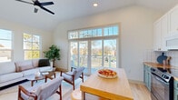 Located in Columbus, Ohio's vibrant East Side, this thoughtfully designed single-floor residence offers a bright and contemporary living experience. The open living area is a standout, featuring vaulted ceilings, light hardwood floors, and a dramatic floor-to-ceiling window with transom panels that frame sweeping views of the surrounding neighborhood and flood the space with natural light. A ceiling fan adds a practical touch to the airy room, which flows seamlessly to an outdoor balcony. The kitchen is a functional and stylish centerpiece, outfitted with two-tone cabinetry — teal lower cabinets paired with crisp white uppers — butcher block countertops, a classic white tile backsplash, and open shelving. A central island with bar stools makes it ideal for casual dining. Adjacent utility cabinetry in dark tones with warm wood countertops provides additional storage. The bedroom is a calm retreat, bathed in natural light from dual windows and offering generous closet space. The en-suite bathroom features a warm wood vanity, white quartz countertop, matte black fixtures, and a bold sage green accent wall, adding a modern, refined touch. A well-lit hallway connects all spaces with clean architectural lines throughout.