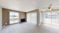 This single-story 2-bedroom, 3-bathroom residence is thoughtfully laid out across a comfortable footprint, offering a practical and cohesive living environment. The living room serves as the heart of the home, featuring plush wall-to-wall carpeting, a textured ceiling, and a wood-burning fireplace set on a brick hearth. Multiple windows and a sliding glass door dressed with vertical blinds fill the space with natural light and provide direct outdoor access and exterior views. A second sliding glass door is found in one of the bedrooms, further connecting the interior to the outside. Both bedrooms are carpeted and equipped with ceiling fans with light fixtures, offering a comfortable and functional retreat. The primary bedroom includes a spacious sliding-door closet, while the secondary bedroom also features closet storage. Three bathrooms serve the residence, including one with a tub-shower combination accented by white tile surround, and another featuring a standalone shower unit with wood-look flooring. Granite-style countertops are noted in the bathroom vanity areas. A kitchen, hallways, and additional closets round out the floor plan, providing ample storage and circulation throughout. The overall aesthetic is neutral and move-in ready, with warm beige tones throughout.