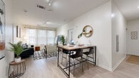 Located at 1060 Fraternity Cir in Kent, Ohio, this thoughtfully designed three-bedroom, three-bathroom unit offers a well-organized single-floor layout. The open-concept living and dining area serves as the heart of the home, featuring light hardwood-style flooring, track lighting, and a bank of large windows dressed with sheer white curtains and wood-slat blinds that flood the space with natural light. The dining area accommodates a bar-height table with seating, complemented by a decorative round mirror shelf on the wall.

The kitchen runs along a galley-style corridor with dark espresso cabinetry, granite countertops, and stainless steel appliances, including a range, microwave, and oven. The clean white walls and recessed lighting keep the space feeling bright and functional.

Each of the three bedrooms features plush carpet flooring, windows with outdoor views of surrounding trees, and access to dedicated closets — some outfitted with built-in shelving. The bedrooms are well-suited for both rest and study, with space for a desk and personal storage.

The bathrooms mirror the kitchen's aesthetic, featuring dark wood vanities with granite countertops, large mirrors, and tub-shower combinations. Decorative accents throughout, including woven shelving and potted greenery, give the bathrooms a warm, polished feel.