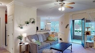 Located at 901 Falls Park Dr in Sanford, NC, this single-floor residence offers a well-designed layout that balances comfort and functionality. The living room serves as the heart of the home, featuring crown molding, a ceiling fan, and plush carpeting. Natural light fills the space, which opens directly to a private balcony through a teal-accented glass door — perfect for enjoying outdoor views. Wall-mounted decor and greenery add a welcoming, lived-in charm.

Adjacent to the living area, the kitchen is outfitted with warm wood cabinetry, white appliances, and light tile flooring. A breakfast bar peninsula provides a seamless connection to the living space, while a separate dining nook — brightened by a large window and a decorative pendant light — offers a dedicated area for meals and workspace.

The residence includes two carpeted bedrooms, each with ample natural light from sizable windows dressed with curtain panels and blinds. Both rooms provide a calm, restful atmosphere with ceiling fans overhead.

A hallway bathroom features warm wood vanity cabinetry, a dual-mirror setup, and tile flooring, connecting conveniently to the bedroom corridor. Crown molding and consistent neutral tones throughout the home create a cohesive, polished aesthetic from room to room.
