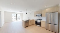 Located at 922 N Broad St in Philadelphia's vibrant Northern Liberties neighborhood, this modern one-bedroom, one-bathroom unit offers a thoughtfully designed single-floor layout with clean contemporary finishes. The open-concept kitchen and living area serves as the heart of the unit, featuring light wood cabinetry, a white quartz peninsula with an undermount sink, stainless steel appliances including a gas range, microwave, dishwasher, and French door refrigerator, and a white subway tile backsplash. Dual pendant lights hang above the peninsula, adding a stylish focal point. Light hardwood flooring flows throughout the entire unit, lending warmth and continuity. The living area is bathed in natural light from large sliding glass doors that open directly onto a private balcony with city views. The bedroom is a well-proportioned, serene retreat with neutral tones, recessed lighting, a ceiling-mounted HVAC unit, and its own access to the balcony. A dedicated walk-in closet offers built-in shelving and multiple hanging rods for ample storage. The full bathroom features marble-style tile flooring, a floating wood vanity with a white countertop, and a glass-enclosed walk-in shower. In-unit laundry adds everyday convenience to this well-appointed urban residence.
