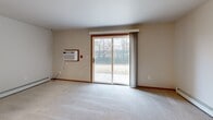 Located at 540 McKinley Ave in Clintonville, Wisconsin, this single-floor, 2-bedroom, 1-bathroom unit offers a practical and comfortable layout throughout. The combined kitchen and living area forms the heart of the home, with the kitchen featuring warm oak cabinetry, black appliances including a refrigerator, dishwasher, and electric range with built-in microwave, and wood-look luxury vinyl flooring. The living room is generously sized and bathed in natural light, with plush carpet underfoot and a large sliding glass door that opens to an outdoor patio area with views of surrounding greenery. A wall-mounted AC unit provides additional climate control alongside baseboard heating found throughout the unit. Both bedrooms are well-proportioned, carpeted, and equipped with ceiling fans and natural light from windows. The primary bedroom features a walk-in closet with built-in shelving and hanging rods, offering ample storage. A second closet provides additional organization space. The full bathroom showcases wood-look tile flooring, oak vanity cabinetry, a soaking tub with grab bar, and a clean, neutral finish. Warm wood trim accents and a consistent neutral color palette tie the space together, creating a cohesive and move-in-ready living environment.
