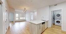 This well-designed two-bedroom, two-bathroom unit at 9660 229 St NW offers a thoughtfully laid-out single-level floor plan. The open-concept kitchen and living area serves as the heart of the space, featuring a large central island with a quartz countertop, undermount sink, and integrated dishwasher. Light wood cabinetry, a classic white subway tile backsplash, and a full suite of stainless steel appliances — including a refrigerator, electric range, and built-in microwave — complete the kitchen. Light hardwood flooring flows consistently throughout the unit, creating a cohesive and bright aesthetic.

The living room receives natural light through a window fitted with modern zebra blinds, and a geometric pendant light adds a contemporary touch. Both bedrooms are comfortably sized with windows and baseboard heating. The two bathrooms are finished with wood-toned vanities, quartz countertops, and full soaker tub and shower combinations. A dedicated laundry area houses a stacked Samsung washer and dryer. Two closets and two hallways provide practical storage and circulation throughout the unit.