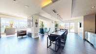 Located at 2155 Kettner Blvd in San Diego's vibrant Little Italy neighborhood, this contemporary amenity space offers a well-appointed, open-plan layout across a single floor. The interior design is clean and modern, featuring wide-plank hardwood flooring, recessed lighting, and a neutral color palette accented by bold design elements throughout.

The kitchen area is a standout feature, showcasing stainless steel cabinetry and appliances, dark countertops, and a dramatic floor-to-ceiling gold and black abstract wall mural that serves as a striking focal point. A long communal dining table with pendant lighting overhead seats numerous guests, making it ideal for gatherings and events. Sliding glass doors at the far end of the dining area provide direct access to an outdoor terrace, flooding the interior with natural light.

An adjacent lounge area features a full-size pool table beneath industrial-style pendant lights, surrounded by floor-to-ceiling windows that frame views of the San Diego skyline and neighboring architecture. A built-in cue rack and high-top seating with glass-top tables complete the game room feel.

The space also includes a secondary lounge nook with teal accent chairs and curated wall art, a built-in bar counter with open wood shelving, and a covered exterior entry area with large-format tile flooring. The overall ambiance is sophisticated, social, and thoughtfully designed for both relaxation and entertainment.