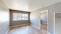 Located at 316–324 Lincoln St in Santa Cruz, California, this efficiently designed one-bedroom, one-bathroom unit offers a thoughtful layout across a single floor. The interior features a consistent, modern aesthetic with light wood-look luxury vinyl flooring running throughout the main living areas and bedroom, complemented by neutral gray wall tones and crisp white baseboards.

The living room serves as the central gathering space, offering a welcoming atmosphere with natural light filtering in through large windows that frame views of the surrounding neighborhood. The bedroom is a well-proportioned private retreat, also finished with the same wood-look flooring and a generously sized window that brings in ample daylight. A dedicated closet provides practical storage.

The bathroom is cleanly appointed with a white vanity cabinet featuring a single undermount sink and stone-look countertop, a large mirror with overhead lighting, tile flooring, and a glass-door shower enclosure with tile surround — all combining to create a functional and polished space.

Throughout the unit, the cohesive use of gray tones, updated fixtures, and durable flooring materials gives the space a refreshed, move-in-ready character. The overall layout maximizes efficiency while maintaining a comfortable and livable feel for its scale.