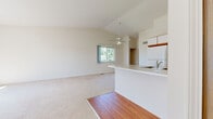 This two-floor residence offers a thoughtfully designed layout with a bright, open feel throughout. The main level centers around an open-concept living and kitchen area, where soaring vaulted ceilings and a ceiling fan create an airy atmosphere. The kitchen is well-equipped with ample white cabinetry accented by warm wood trim, generous counter space, a coil-top range, refrigerator, and a peninsula with a built-in sink that seamlessly connects to the living area. Wood-look flooring runs through the kitchen, transitioning to plush carpeting in the living space. A window brings in natural light and views of surrounding greenery. A convenient half bathroom with wood-look flooring and vanity storage is also found on this level. The upper floor features generously sized carpeted bedrooms, each filled with natural light from large windows overlooking lush outdoor scenery. A full bathroom on this level includes a wide vanity with ample cabinet storage, a large mirror, and a tub-shower combination. A standout feature of the upper floor is a sun-drenched room with a sliding glass door opening to a private balcony, offering pleasant outdoor views. The overall palette of neutral whites and warm wood tones creates a clean, versatile ambiance throughout the home.