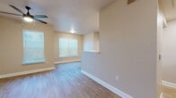 This single-floor residence offers a practical and comfortable layout with 2 bedrooms and 2 bathrooms. The open-concept living, dining, and kitchen area forms the heart of the home, featuring warm-toned wood-look flooring throughout, neutral beige walls, and ceiling fans that enhance airflow and comfort. Multiple windows fitted with blinds allow natural light to fill the space.

The kitchen is equipped with rich wood cabinetry, white appliances including a refrigerator, electric range, and microwave, and a peninsula with a breakfast bar that connects seamlessly to the living and dining areas. A dedicated pantry and an in-unit laundry area add to the home's functionality.

The generously sized primary bedroom features two windows, a ceiling fan, and direct access to its en-suite bathroom. The bathroom includes a wood-vanity with a single sink, stone-look countertop, and a walk-in shower with tile surround and grab bars. Both bathrooms maintain a consistent, clean aesthetic.

Storage is a standout feature, with five closets throughout the residence, including walk-in closets equipped with multi-tier wire shelving systems for organized storage. A connecting hallway ties the bedrooms and bathrooms together efficiently, completing this well-designed and functional home.