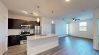 Located at 2808 E McKinney St in Denton, TX, this well-designed 2-bedroom, 3-bathroom residence offers a thoughtfully arranged single-floor layout that maximizes both function and style. The open-concept living and kitchen area serves as the heart of the home, anchored by a large granite-topped island with a built-in sink and pendant lighting above. The kitchen features rich dark cabinetry, stainless steel appliances including a refrigerator, range, and microwave, plus track lighting that adds a contemporary touch. Wood-look flooring flows seamlessly throughout the space, complementing the clean, neutral color palette. The living area benefits from natural light and is equipped with a ceiling fan for added comfort. The primary bedroom is a well-proportioned retreat with its own ceiling fan and access to a dedicated closet. The primary bathroom includes a granite vanity with dark cabinetry, a soaking tub, tiled shower surround, and direct access to a walk-in closet with built-in shelving. The second bedroom also features wood-look flooring, a window with outdoor views, and ceiling fan. Additional closet storage and three full bathrooms round out this efficiently designed and modern residence.