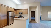 Located at 300 Crescent Dr in Vacaville, CA, this well-appointed 2-bedroom, 2-bathroom residence offers a comfortable and functional single-level layout. The open living room is a standout, featuring soaring vaulted ceilings, a ceiling fan, plush carpeting, and a tile-surround gas fireplace with a built-in media niche above. Sliding glass doors lead to a private balcony with neighborhood views, allowing natural light to fill the space. The kitchen is designed for efficiency and style, featuring warm honey-toned cabinetry extending to the ceiling, granite-style countertops, stainless steel appliances including a refrigerator, microwave, and range, as well as a dishwasher and sink. A pass-through counter connects the kitchen to the living area. Both bedrooms are carpeted and well-lit by windows with blinds, offering a quiet retreat. The spacious primary bedroom includes generous closet storage. Two full bathrooms complete the layout, each finished with warm tile flooring and rich wood cabinetry. One bathroom features a soaking tub/shower combination. Two closets and a hallway provide ample storage and circulation throughout this well-organized home.