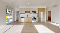 Located at 634 S 400 W in Salt Lake City, Utah, this contemporary 2-bedroom, 2-bathroom residence offers a well-designed single-floor layout with clean, modern finishes throughout. Light wood-tone flooring flows seamlessly across the open-concept kitchen and living area, which serves as the heart of the home. The kitchen is outfitted with warm natural wood cabinetry, a textured tile backsplash, stainless steel appliances including a refrigerator, range, microwave, and dishwasher, and recessed lighting overhead. The living area is bathed in natural light through large sliding glass doors and oversized windows that frame city views, with direct access to a spacious tiled patio overlooking the Salt Lake City skyline and the Wasatch Mountain range beyond. The primary bedroom features generous proportions, a sliding barn door, and access to outdoor views, while the second bedroom benefits from floor-to-ceiling windows with urban street views. Two well-appointed bathrooms include warm wood vanities with clean white countertops and matte black fixtures; one features a full soaking tub with vertically tiled surround. Multiple closets provide ample storage, and hallways connect the layout efficiently. The overall aesthetic is bright, minimal, and contemporary.