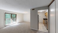 This single-floor residence offers a thoughtfully designed layout that balances comfort and functionality throughout. The spacious living room serves as the heart of the home, featuring neutral-toned carpet, a textured ceiling, and a sliding glass door that opens to a private balcony overlooking lush greenery, allowing natural light to fill the space. The kitchen is efficiently appointed with warm oak cabinetry, dark granite countertops, and a full suite of stainless steel appliances including a refrigerator, electric range, and dishwasher. Light tile flooring and an under-cabinet range hood complete the practical yet attractive kitchen space. The bedrooms are carpeted and bright, each offering large windows that frame views of surrounding trees. Sliding panel closets provide generous storage in the bedrooms. The bathroom features a full tub-shower combination, tile flooring, and a vanity with dark granite countertops that coordinate with the kitchen's finishes, creating a cohesive aesthetic throughout the home. Neutral wall tones and consistent finishes across all rooms contribute to a clean, move-in-ready ambiance that is both versatile and welcoming.