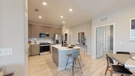 This thoughtfully designed single-floor residence offers a cohesive blend of modern aesthetics and functional living. The open-concept kitchen is a standout feature, outfitted with flat-panel wood-tone cabinetry, white quartz countertops, a subway tile backsplash, and a full suite of stainless steel appliances. A central island with bar seating provides additional workspace and a casual dining option, while light wood-look flooring flows seamlessly throughout the space. The adjacent dining area offers an intimate setting with ample natural light and direct sightlines to the living spaces. The living room makes a bold design statement with a deep navy accent wall, ceiling fan, and large windows that allow natural light to fill the room. The bedrooms are serene and comfortable, each equipped with ceiling fans, generous windows, and access to walk-in closets featuring wire shelving systems. The primary en-suite bathroom is elegantly finished with wood-tone vanity cabinetry, white quartz countertops, a frameless glass walk-in shower with large-format tile, and light wood-look tile flooring that extends the home's cohesive palette. Recessed lighting throughout ensures a bright, welcoming ambiance in every room.