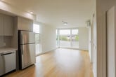 Located at 2650 Telegraph Ave in Berkeley, California, this modern one-bedroom, one-bathroom unit offers a thoughtfully designed layout with clean lines and a bright, contemporary aesthetic throughout. Light hardwood flooring flows seamlessly across the entire space, complementing the crisp white walls and creating a warm, cohesive feel.

The open-concept kitchen and living area serves as the heart of the unit. The kitchen is outfitted with a full suite of stainless steel appliances, including a refrigerator, range, microwave, and dishwasher. Flat-front cabinetry in a soft gray-beige tone extends to the ceiling, maximizing storage, while a subtle tile backsplash adds texture. White quartz countertops and recessed lighting complete the polished look. Large floor-to-ceiling windows in the living area flood the space with natural light and offer views of the surrounding neighborhood's greenery.

The bedroom is a well-proportioned, tranquil retreat featuring a window with outdoor views and a dedicated closet with built-in hanging storage. The bathroom is clean and functional, with a single vanity with under-sink cabinetry, a large mirror, and a tub-shower combination enclosed by a glass sliding door. Every room reflects a consistent modern design sensibility, making this a comfortable and stylish urban residence.