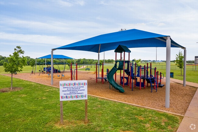 A playground area is located next to the covered pavilion at the Kaufman Sports Complex.