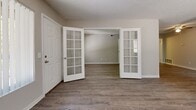 Located at 8490 Sheridan Blvd in Arvada, Colorado, this two-bedroom, one-bathroom single-floor residence offers a practical and comfortable layout. The living room serves as the heart of the home, highlighted by a tile-surround wood-burning fireplace, wood-look plank flooring, and a large window that fills the space with natural light. A distinctive set of white French doors with glass panes connects the entryway to the living area, adding a charming architectural touch. The kitchen features warm wood cabinetry, a skylight-style ceiling detail for added brightness, a pass-through counter that opens to the dining area, and appliances including a refrigerator and range. The open connection between the kitchen and dining space supports an easy flow for daily living. The spacious primary bedroom includes a window with outdoor views and direct access to closet space. The second bedroom is similarly bright, with a window overlooking greenery and its own closet. The shared bathroom is clean and functional, featuring a full tub-shower combination with white tile surround and brushed nickel fixtures. A dedicated utility room provides additional storage and convenience. Textured ceilings and neutral-toned walls carry throughout, creating a cohesive and move-in ready environment.
