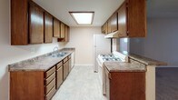 This single-story residence offers a practical and cohesive layout with consistent finishes throughout. The galley-style kitchen is efficiently designed with warm oak cabinetry lining both walls, providing generous storage above and below the laminate countertops. A double basin sink, gas range, and refrigerator are included, while a skylight overhead floods the space with natural light, complementing the light tile flooring.

The living area is generously proportioned, featuring plush wall-to-wall carpeting, a textured ceiling, and vertical blinds covering a sliding glass door that allows natural light to filter in. The open layout connects seamlessly to adjacent spaces, enhancing the overall sense of flow.

The carpeted bedrooms are comfortably sized, with neutral walls and textured ceilings. One bedroom features a ceiling fan with integrated lighting. Multiple windows dressed with vertical blinds allow natural light and outdoor views into the rooms, creating a bright and airy atmosphere.

The bathroom is accessed through a sliding door and features a solid wood vanity with a single sink set in stone-patterned countertop, a Hollywood-style vanity light bar, a large mirror, and light tile flooring, providing a clean and functional space.