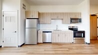 Located in Pittsburgh's vibrant Strip District, this modern 2-bedroom, 2-bathroom unit offers a well-designed single-floor layout with clean, contemporary finishes throughout. The open-concept kitchen and living area serves as the heart of the home, featuring light wood cabinetry, white subway tile backsplash, quartz countertops, and a full suite of stainless steel appliances including a dishwasher, range, microwave, and refrigerator. Light hardwood-style flooring runs through the main living spaces, adding warmth to the bright, neutral palette. Both bedrooms are carpeted for comfort and feature exposed industrial-style ductwork that adds a modern edge, along with windows that bring in natural light and views of the surrounding neighborhood. The two bathrooms are finished with light wood vanities, white quartz countertops, and full tub-shower combinations. A dedicated in-unit laundry closet with a front-load washer adds everyday convenience. Four closets provide ample storage throughout the unit. The building offers access to a spacious rooftop deck with wood-plank flooring, open sky views, and sweeping vistas of the Pittsburgh skyline and surrounding hills—an exceptional outdoor amenity for urban living.