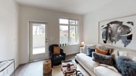 This single-story Uptown residence offers a thoughtfully designed one-bedroom, one-bathroom layout with a clean, contemporary aesthetic throughout. The living area is bright and welcoming, featuring wood-style flooring, crisp white walls, and large windows that allow abundant natural light and outdoor views of the surrounding neighborhood. A glass-panel door provides direct access to a private outdoor space, enhancing the connection between interior and exterior.

The kitchen is well-appointed with light wood-toned cabinetry, white quartz countertops, and a classic subway tile backsplash. A full suite of stainless steel appliances includes a refrigerator, electric range, over-the-range microwave, and dishwasher, providing a functional and modern cooking environment.

The bedroom is a serene, carpeted retreat with a large window overlooking greenery. A standout feature is the sliding barn-style door leading to a generously sized walk-in closet with built-in shelving and hanging space.

The bathroom is finished with the same light wood cabinetry as the kitchen, complemented by white quartz countertops, a large vanity mirror, and a full tub-shower combination with chrome fixtures. The cohesive material palette across the unit creates a polished, unified living environment.