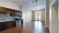 This single-story, 2-bedroom, 2-bathroom residence offers a thoughtfully designed layout that maximizes comfort and functionality. The open-concept kitchen and living area serves as the heart of the home, featuring rich hardwood-style flooring, soaring ceilings, and an abundance of natural light. The kitchen is outfitted with dark espresso cabinetry, granite countertops, a subway tile backsplash, and stainless steel appliances, including a refrigerator, electric range with microwave, and dishwasher. The living area extends toward a set of French doors that invite natural light and outdoor views, and is equipped with a ceiling fan and track lighting overhead. Both bedrooms are generously sized, finished with plush carpeting, ceiling fans, and windows with outdoor views. Each bedroom is paired with its own private bathroom, featuring dark cabinetry with granite countertops and tile-surround walk-in showers. Both bedrooms also include dedicated walk-in closets outfitted with wire shelving systems for organized storage. The overall aesthetic is cohesive and modern, with neutral tones throughout creating a warm and inviting ambiance across the entire residence.