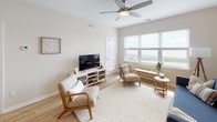 This single-floor residence offers a thoughtfully designed layout with a clean, neutral aesthetic throughout. The kitchen is a functional highlight, featuring white shaker-style cabinetry, granite countertops, stainless steel appliances including a gas range and French door refrigerator, and light wood-style flooring that extends into the adjoining living areas. A pendant light and recessed lighting add warmth to the space.

The living area is bright and welcoming, benefiting from large windows dressed with blinds that invite ample natural light. A ceiling fan overhead adds comfort, while the open layout provides flexibility for a variety of furniture arrangements. A secondary sitting area offers additional lounging space with its own window.

The bedrooms are carpeted for comfort, each featuring windows that bring in natural light. The primary bedroom is generously sized with room for a large bed and dresser. An additional carpeted room serves well as a guest bedroom, home office, or flex space.

Two bathrooms are finished with granite countertops, white cabinetry, framed mirrors, and chrome fixtures. One bathroom includes a shower/tub combination, while the other features a walk-in shower. Both offer wood-look flooring and clean, modern finishes throughout, contributing to the overall cohesive and polished feel of the home.