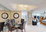 Located at 3710 Inverrary Dr in Lauderhill, FL, this well-appointed single-floor residence offers a thoughtfully designed open layout that maximizes every inch of its footprint. The combined living and dining area is anchored by large white floor tiles that run throughout the space, creating a bright and cohesive aesthetic. A tray ceiling with a contemporary light fixture adds architectural interest to the dining area, while floor-to-ceiling mirrored panels visually expand the living space and enhance natural light.

The kitchen is sleek and modern, outfitted with white cabinetry, light quartz countertops, a subway tile backsplash, and a full suite of stainless steel appliances including a range, microwave, and dishwasher. The sleeping area is generously sized and benefits from recessed lighting and a ceiling fan, providing both comfort and functionality.

The bathroom features marble-style wall tiles from floor to ceiling, a white quartz vanity, and a tub-shower combination, all finished in a crisp, clean palette. Three closets offer ample storage throughout the unit. A private balcony provides an outdoor retreat, while a dedicated utility room adds practical convenience. The overall ambiance is bright, modern, and efficiently organized.