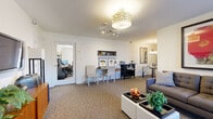 Located at 47 Madison Gardens in Old Bridge, NJ, this efficiently designed single-floor unit offers a thoughtful layout that maximizes every square foot. The space comprises a living room, kitchen, bathroom, and hallway, each finished with care and attention to detail.

The living room serves as the heart of the unit, featuring wall-to-wall carpeting and an open, versatile layout that accommodates both a seating area and a dedicated workspace. A sliding glass door with vertical blinds fills the room with natural light and provides access to an outdoor area. A wall-mounted television, built-in shelving, and warm pendant lighting round out the space's functional appeal.

The galley-style kitchen is thoughtfully appointed with dark cabinetry, white quartz countertops, a subway tile backsplash, and light hardwood-style flooring. A natural light-filled window, full suite of appliances, and a small breakfast bar with seating make the kitchen both practical and inviting.

The bathroom features clean white subway tile walls, a tiled floor, a tub-shower combination with a window, and a dark-cabineted vanity with a white countertop, offering a crisp, well-maintained aesthetic.

The hallway connects the rooms seamlessly, maintaining a consistent, neutral color palette throughout. Overall, the unit presents a clean, modern ambiance suited for comfortable everyday living.