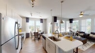Located at 1095 Manhattan Blvd in Dayton, Kentucky, this well-appointed single-floor residence offers a thoughtfully designed open-concept layout that seamlessly connects the kitchen, dining, and living areas. The kitchen is a standout feature, showcasing crisp white cabinetry, light quartz countertops, a classic subway tile backsplash, stainless steel appliances, and a central island with a sink and pendant lighting — ideal for both everyday cooking and entertaining. Track lighting overhead adds a modern touch, while durable wood-look flooring runs throughout the main living spaces. The bright and airy living room is lined with large windows dressed in two-toned navy and sheer curtains, inviting generous natural light and outdoor views. A ceiling fan adds comfort to this welcoming gathering space. The bedrooms are comfortably carpeted, each featuring ample natural light through well-sized windows. One bedroom features a warm accent wall, while another offers a serene neutral palette. The bathrooms are finished with large-format tile and include both a walk-in glass shower and a tub-shower combination, providing versatile options. Wood-look flooring extends into the bathrooms, maintaining a cohesive aesthetic throughout the residence.