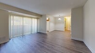 This two-bedroom, one-bathroom residence at 7234 Montgomery Rd in Elkridge, Maryland offers a practical and comfortable single-floor layout. Wood-style plank flooring runs consistently throughout the home, lending a cohesive and clean aesthetic to every room.

The living area is generously sized, featuring a large sliding glass door dressed with vertical blinds that draws in an abundance of natural light and provides an open, airy feel. A pendant light fixture marks the transition toward the kitchen and hallway, giving the space a welcoming focal point.

The kitchen is outfitted with warm oak cabinetry, a gas range, built-in microwave, dishwasher, and refrigerator. A window above the counter area allows natural light to brighten the workspace.

Both bedrooms offer comfortable proportions, with the primary bedroom featuring multiple doors leading to closets and adjoining spaces. The secondary bedroom includes a window with outdoor views, filling the room with natural light. Two closets throughout the unit provide practical storage solutions.

The bathroom is cleanly appointed with tile flooring, a full tub-shower combination, an oak vanity with ample counter space, and a well-lit mirror above. The neutral color palette across the home creates a calm, move-in-ready atmosphere suitable for a variety of living arrangements.