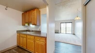 Located at 9231 Independence Blvd in Parma Heights, Ohio, this one-bedroom, one-bathroom unit offers a practical and well-organized single-floor layout. The galley-style kitchen features warm honey-toned wood cabinetry, dark granite-look countertops, a double sink, and white appliances including a range and refrigerator, with durable hardwood-style flooring underfoot. A half-wall pass-through opens the kitchen toward the living area, which is carpeted and filled with natural light from a large sliding glass door that leads to a private balcony overlooking a treed outdoor landscape. A pendant light fixture adds a simple decorative touch to the living space. The bedroom is a comfortable size, carpeted, and includes a sliding-door closet along with a window fitted with vertical blinds that allow for adjustable natural light. The full bathroom is tiled in classic yellow ceramic from floor to mid-wall, and is equipped with accessibility features including grab bars and a step-in bathtub, complemented by a wood-toned vanity with countertop sink. Textured ceilings throughout and clean, neutral wall tones give the unit a consistent, understated character well-suited for functional everyday living.