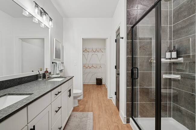 Baño con encimeras de granito, lavabos dobles, ducha amplia y vestidor. - Linz Charlotte