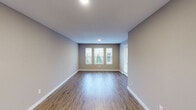 Located at 301 Martha Layne Collins Blvd in Highland Heights, Kentucky, this one-bedroom, one-bathroom unit offers a well-designed single-floor layout with a thoughtful blend of functionality and modern finishes. The living room serves as the heart of the unit, featuring warm hardwood-style flooring, neutral-toned walls, and a trio of windows that invite natural light and outdoor views, creating an open and airy atmosphere. The kitchen is well-appointed with white shaker-style cabinetry, light quartz countertops, and a full suite of stainless steel appliances including a range, over-the-range microwave, refrigerator, and dishwasher. A kitchen island with an undermount sink adds prep space and functionality. Notably, an in-unit washer is conveniently accessible directly from the kitchen area. The bedroom offers a comfortable, carpeted retreat with a window overlooking the outdoors, providing natural light and a peaceful ambiance. The bedroom is complemented by a dedicated closet outfitted with wire shelving and hanging rods, maximizing storage capacity. The bathroom includes a full tub-shower combination with white tile surround and clean, simple finishes. Neutral tones and consistent finishes throughout lend the unit a cohesive and move-in-ready appeal.